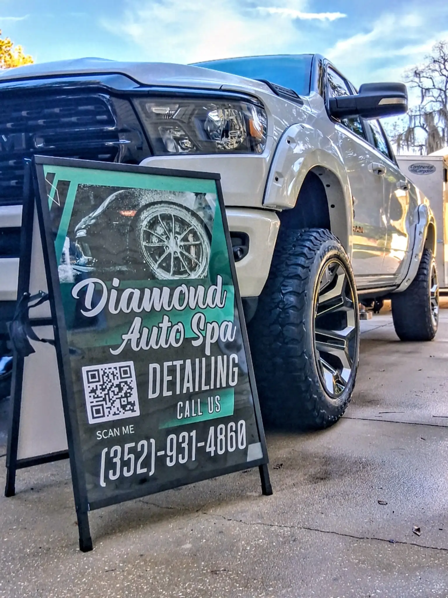 Diamond Auto Spa Detailing sidewalk sign displayed in front of a lifted white RAM pickup truck